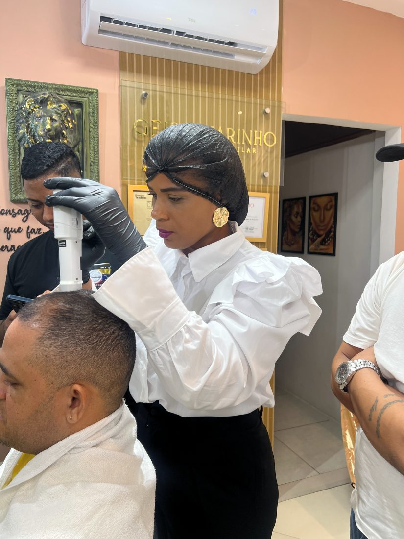 Geisa Marinho avaliando o couro cabeludo de um cliente com microcâmera durante o workshop